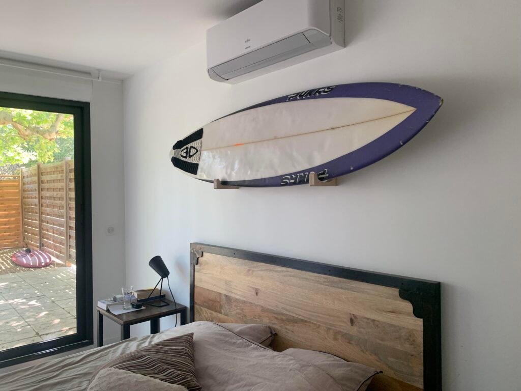Rack de surf mural horizontal en bois installé au-dessus d'un lit