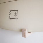 Rack mural de surf en bois. un surf est installé dessus